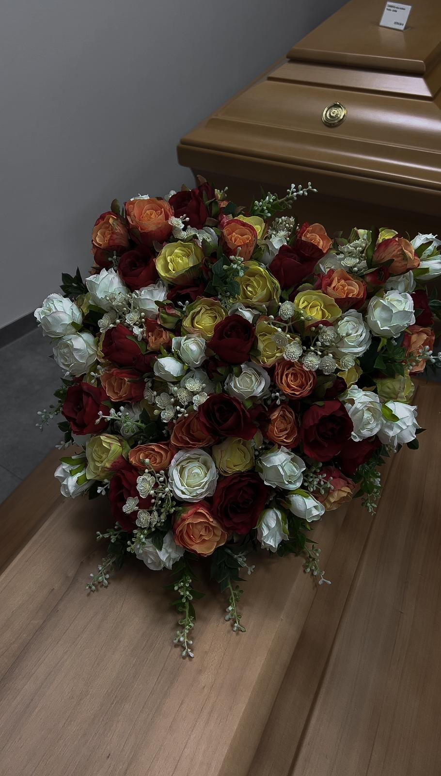 Buntes Blumengesteck auf einem Holzsarg im Bestattungshaus Kinderknecht Nürnberg