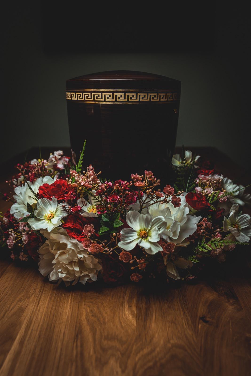 Dunkle Urne mit goldenem Dekor und Blumenkranz – Bestattungen Kinderknecht Nürnberg